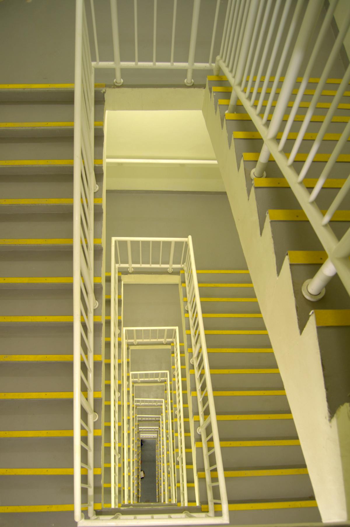 Modernes Treppenhaus von oben mit hellem Geländer und markierten Stufen — Beispielbild Treppenhaus-Reinigung.